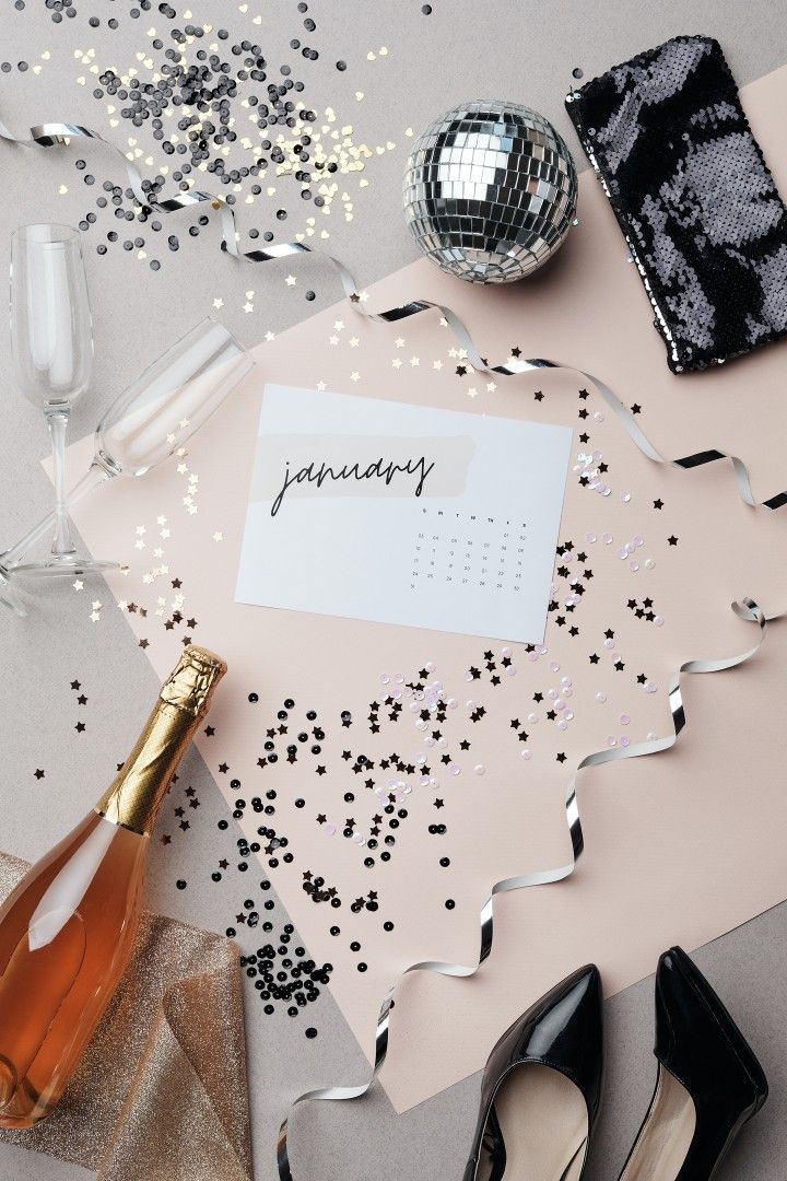Flat lay with January calendar, champagne bottle, confetti and sequined clutch — goal setting for creative entrepreneurs