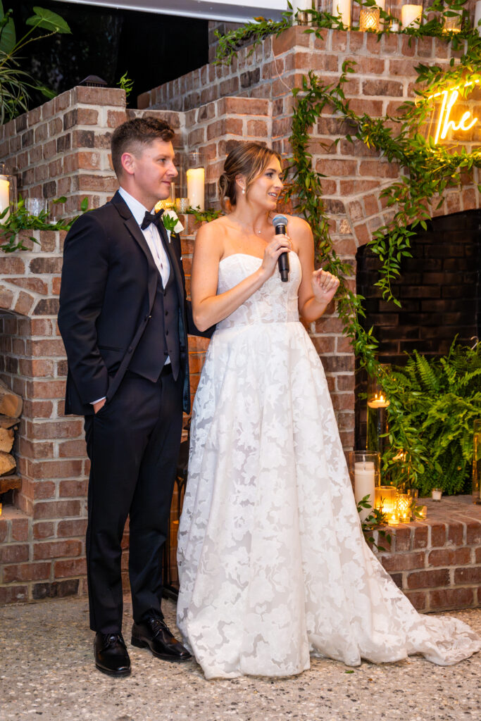 Bride and groom standing together giving a speech during their wedding reception.