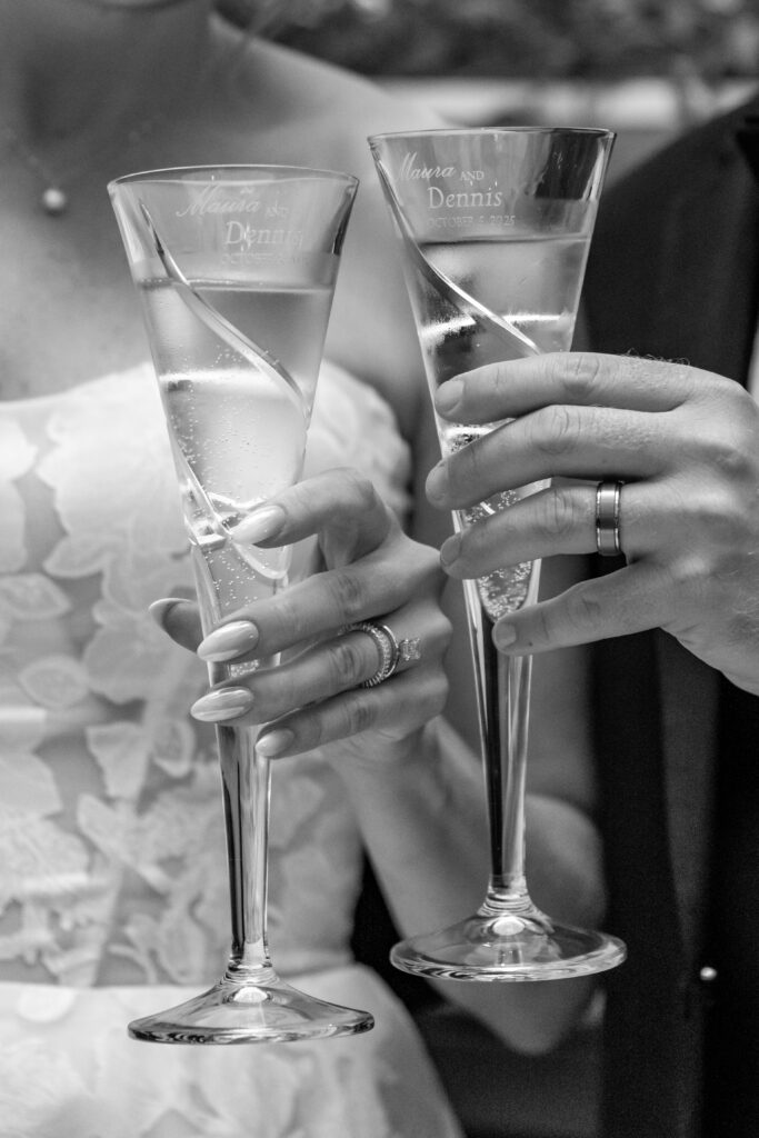 Close-up of engraved champagne flutes held by the bride and groom during their toast.