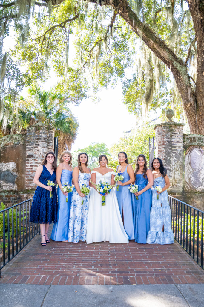 Bride with bridesmaids in shades of blue holding white and green bouquets under Spanish moss trees, photographed by Baltimore wedding photographer Jennifer Mary Collective