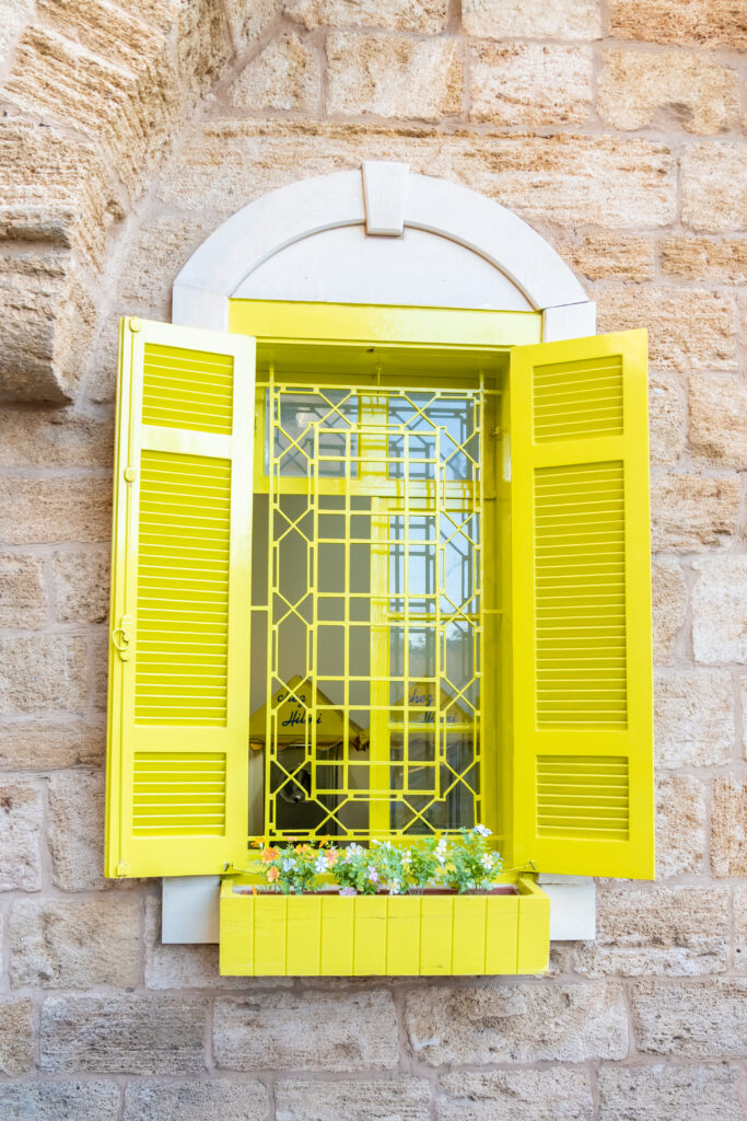 Bright yellow window with flower box on stone building in Beirut Lebanon