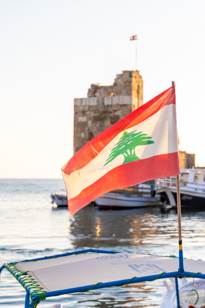 Lebanese flag flying at sea with ancient coastal tower in Lebanon