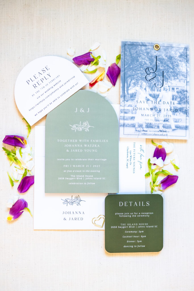 Wedding invitation suite flat lay featuring a sage green arch invitation, save the date, RSVP card, and details card styled with purple and white florals, photographed by Maryland wedding photographer Jennifer Mary Collective