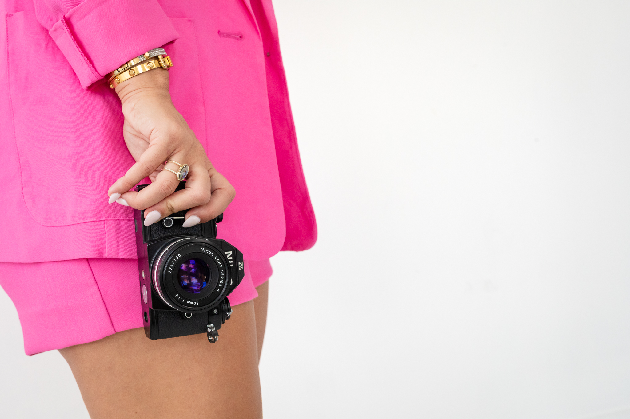 Jen El-Haddad of Jennifer Mary Collective in a pink suit holding a vintage Nikon film camera, from her photography rebrand brand session